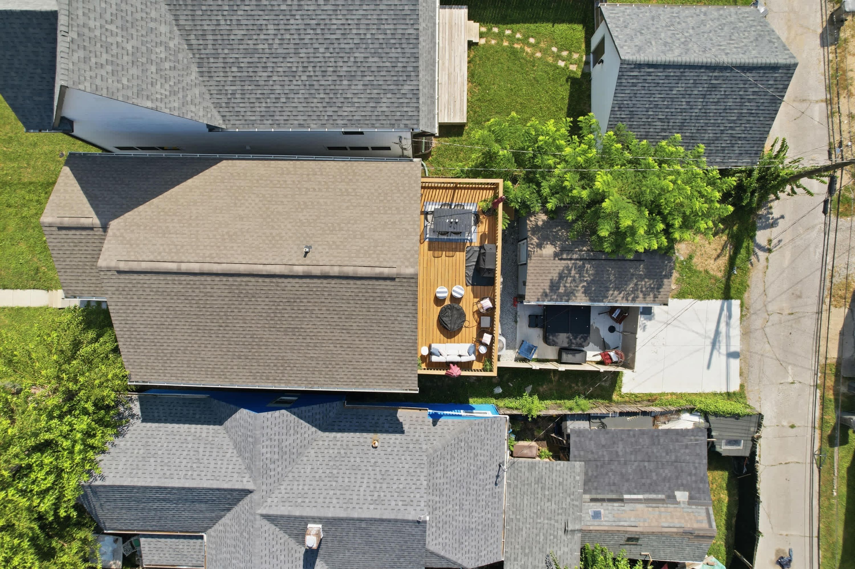 An aerial view of a residential area with multiple houses, a rooftop deck with outdoor furniture, and a small garden area.