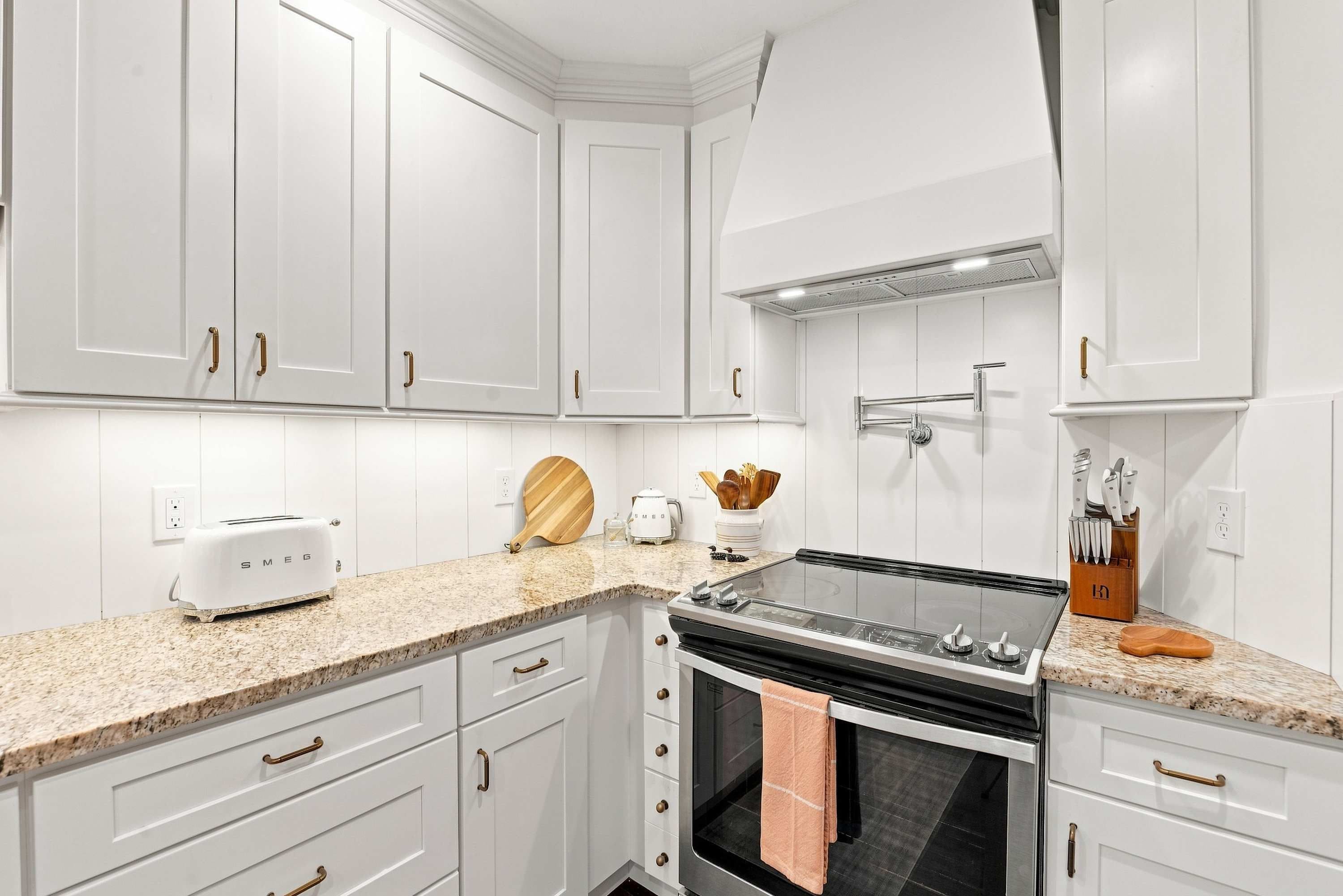 A kitchen with white cabinets, a stove, a toaster, and a coffee maker.