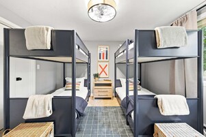 Habitación con literas, una mesita pequeña y una planta entre las camas.