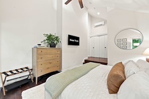 Un dormitorio con cama, cómoda, espejo y televisor.