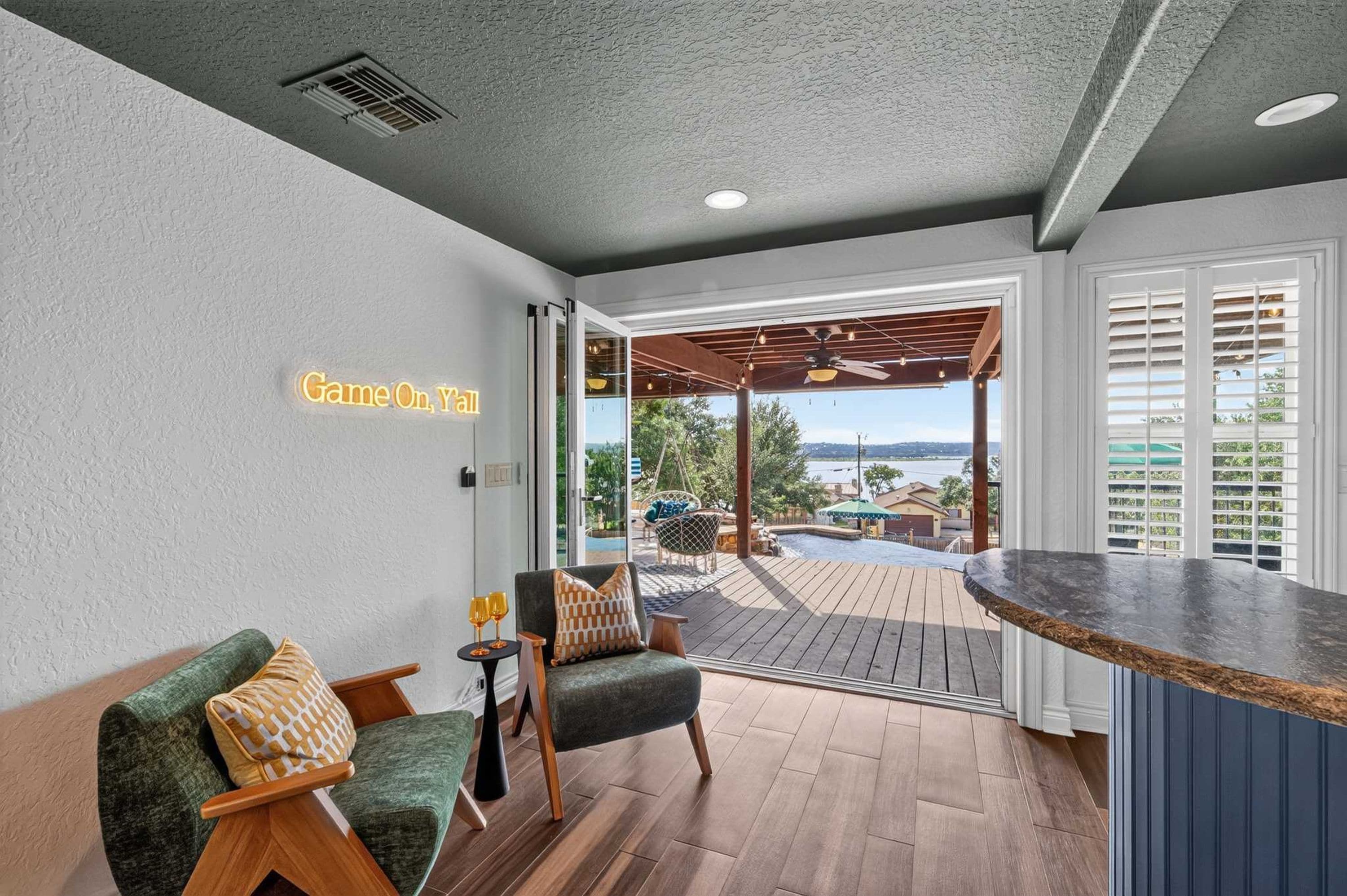 Un interior moderno con una zona de bar, asientos y vistas a una piscina y al paisaje.