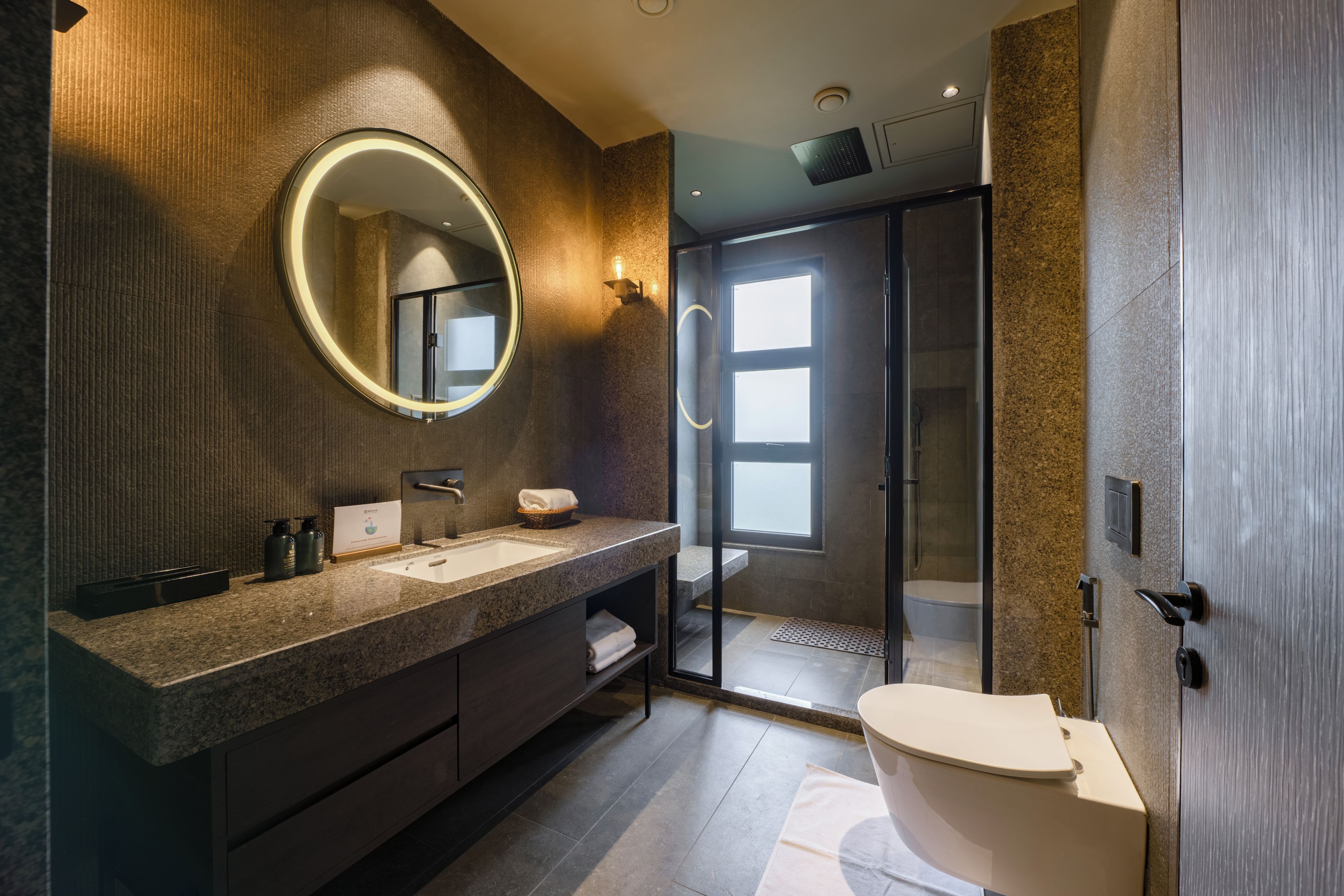 A modern bathroom with a large mirror, a sink, and a toilet.