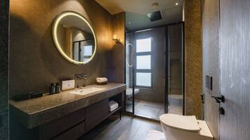 A modern bathroom with a large mirror, a sink, and a toilet.