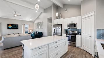 Una cocina moderna con armarios blancos, electrodomésticos de acero inoxidable y una isla central.