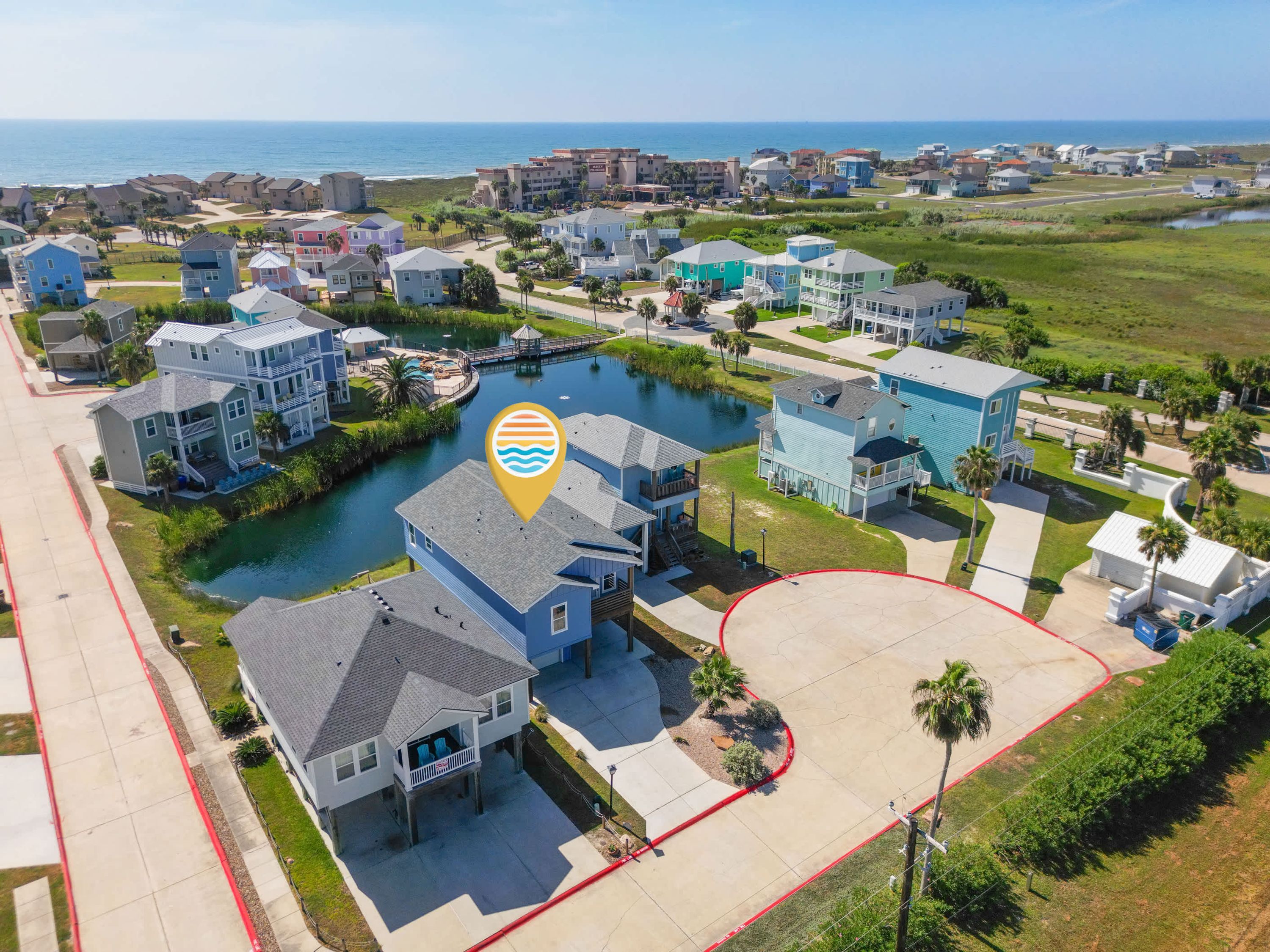 A residential area with houses, a body of water, and a beach in the background.