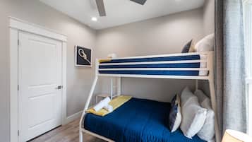 A bunk bed with a blue mattress and white headboard, a ceiling fan, a white door, and a small framed picture on the wall.
