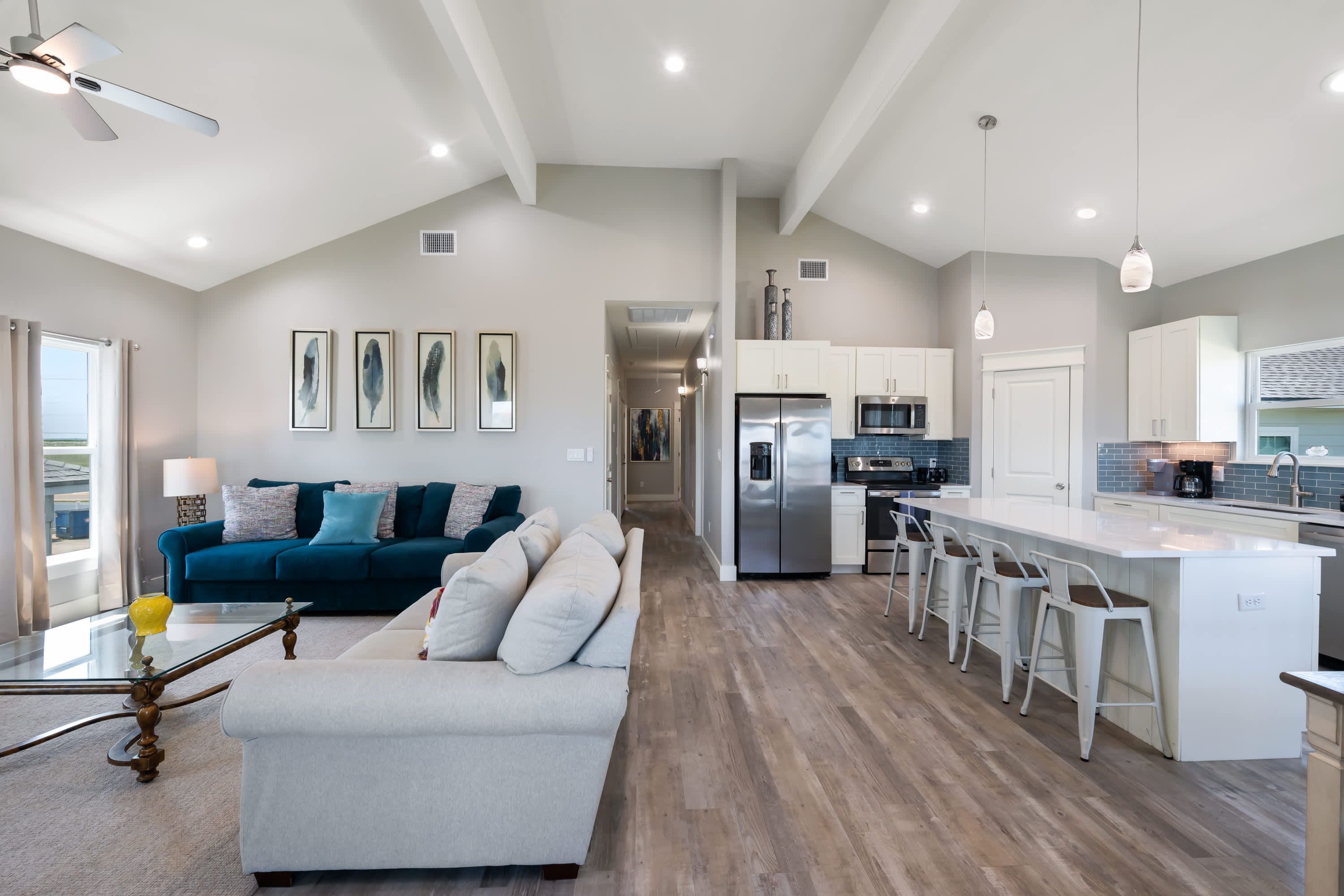 A modern kitchen with a central island, bar stools, and a dining area.