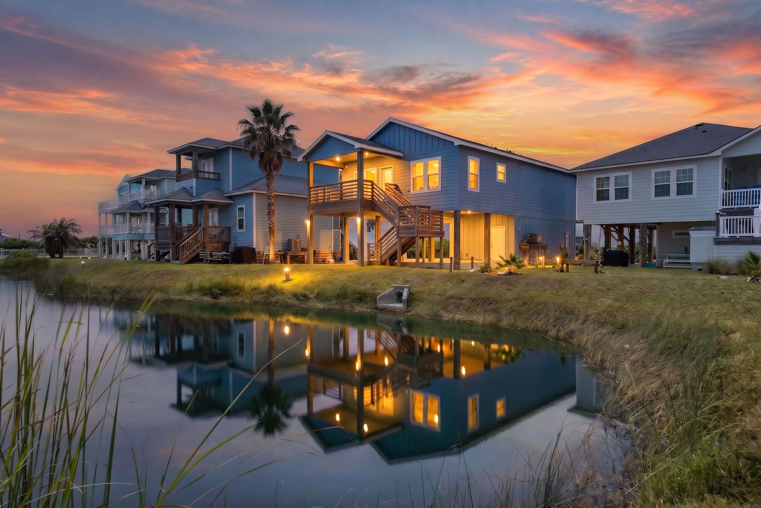 Una propiedad frente al agua con varias casas, un estanque reflectante y un cielo al atardecer.