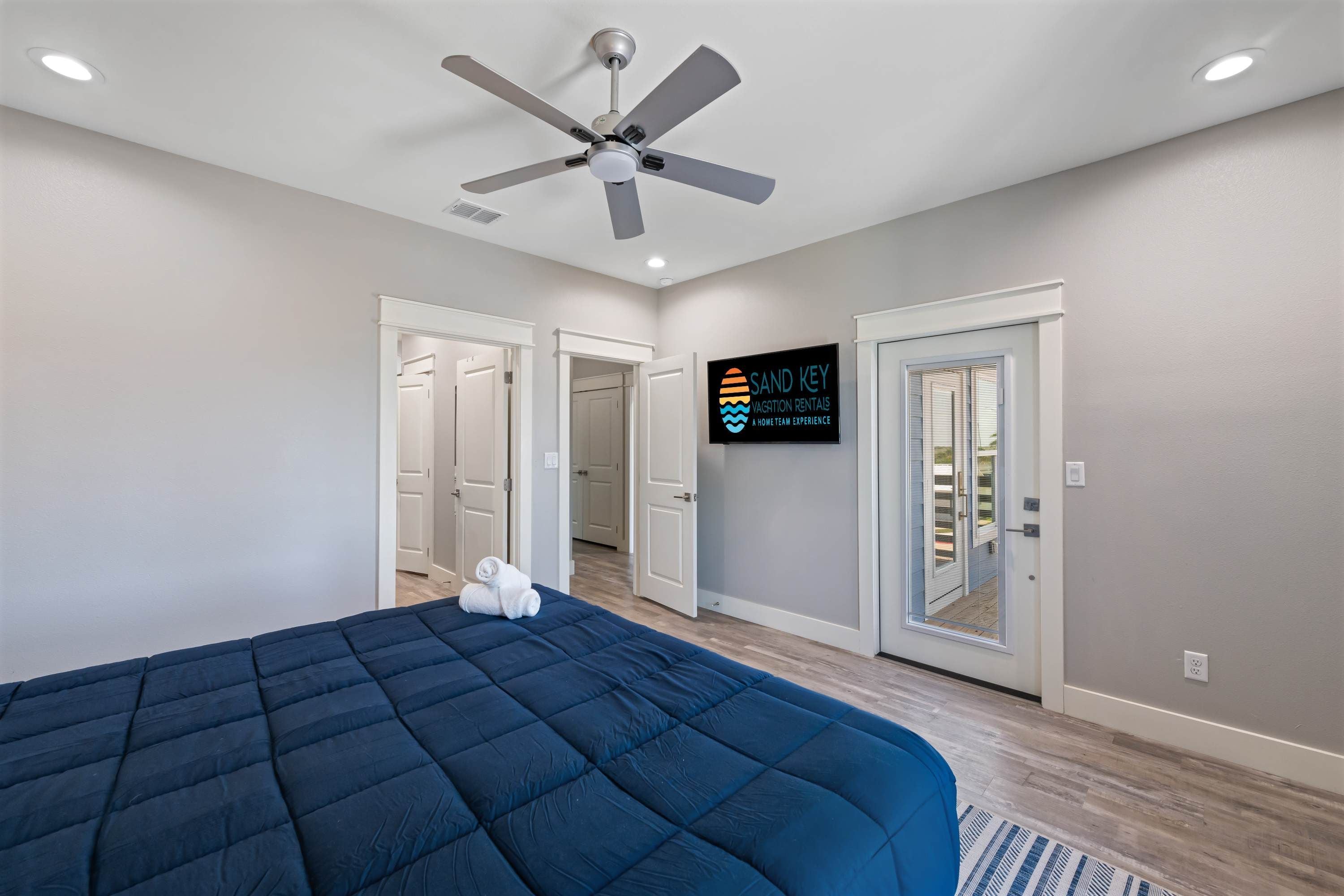 Un dormitorio con cama, ventilador de techo y un cartel de Sand Key Vacation Rentals.