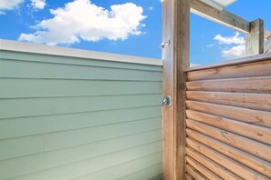 Une porte en bois avec un loquet métallique, située à côté d’un mur recouvert de panneaux de parement de couleur vert clair.