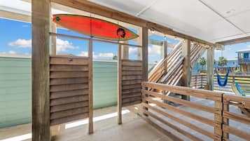 A wooden deck with a surfboard, a staircase, and a view of a building.