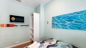 A bedroom with a bed, a wall-mounted TV, a painting, and a bat on the wall.