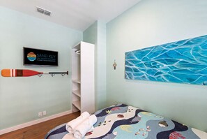 A bedroom with a bed, a wall-mounted TV, a painting, and a bat on the wall. - Port A Vallarta Community Pool Close to Beach (Port Aransas)