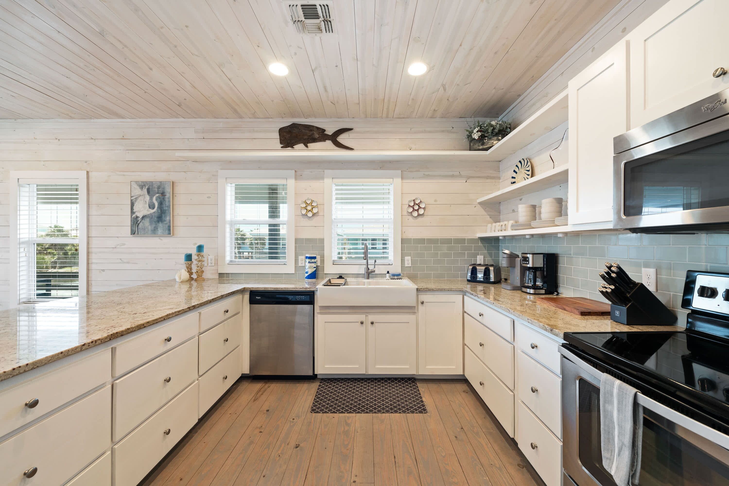 A modern kitchen with white cabinetry, a stainless steel dishwasher, a black stove, and a microwave.