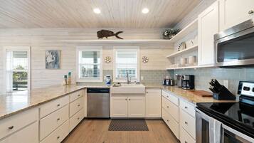 A modern kitchen with white cabinetry, a stainless steel dishwasher, a black stove, and a microwave.