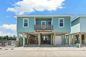 A two-story building with a balcony, a covered area, and a garage. - Port A Vallarta Community Pool Close to Beach (Port Aransas)