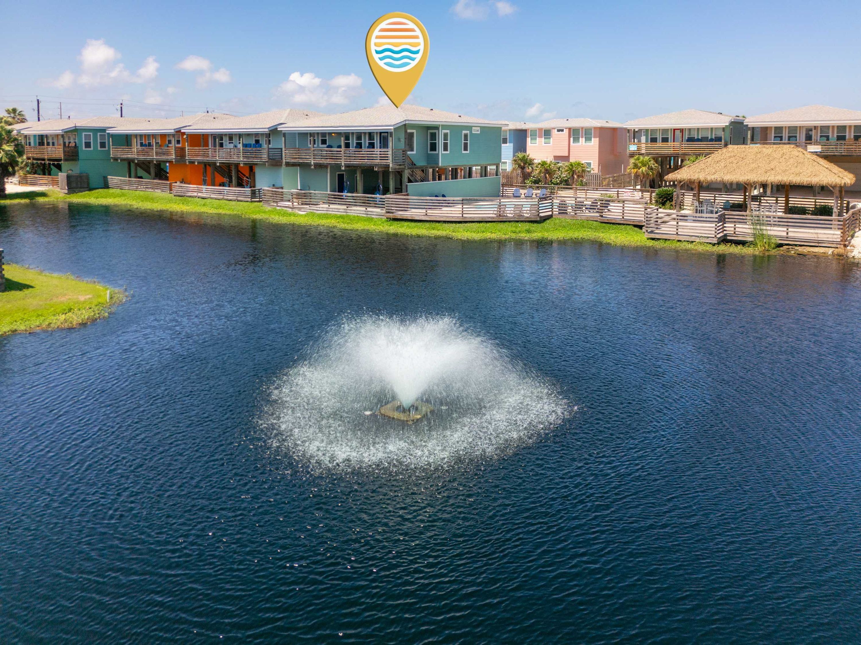 A waterfront property with a central water feature, a pool area, and a row of colorful buildings.