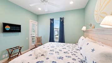 A bedroom with a bed, a ceiling fan, a TV, and a window with curtains.