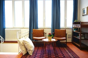 A room with two leather chairs, a small table with a potted plant, a bookshelf, and a radiator. - Sunny & Spacious Apartment in the Heart of Lucca (Lucca)