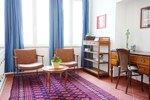 A room with two chairs, a small table with a plant, a bookshelf, a desk with a lamp, and a patterned rug. - Sunny & Spacious Apartment in the Heart of Lucca (Lucca)