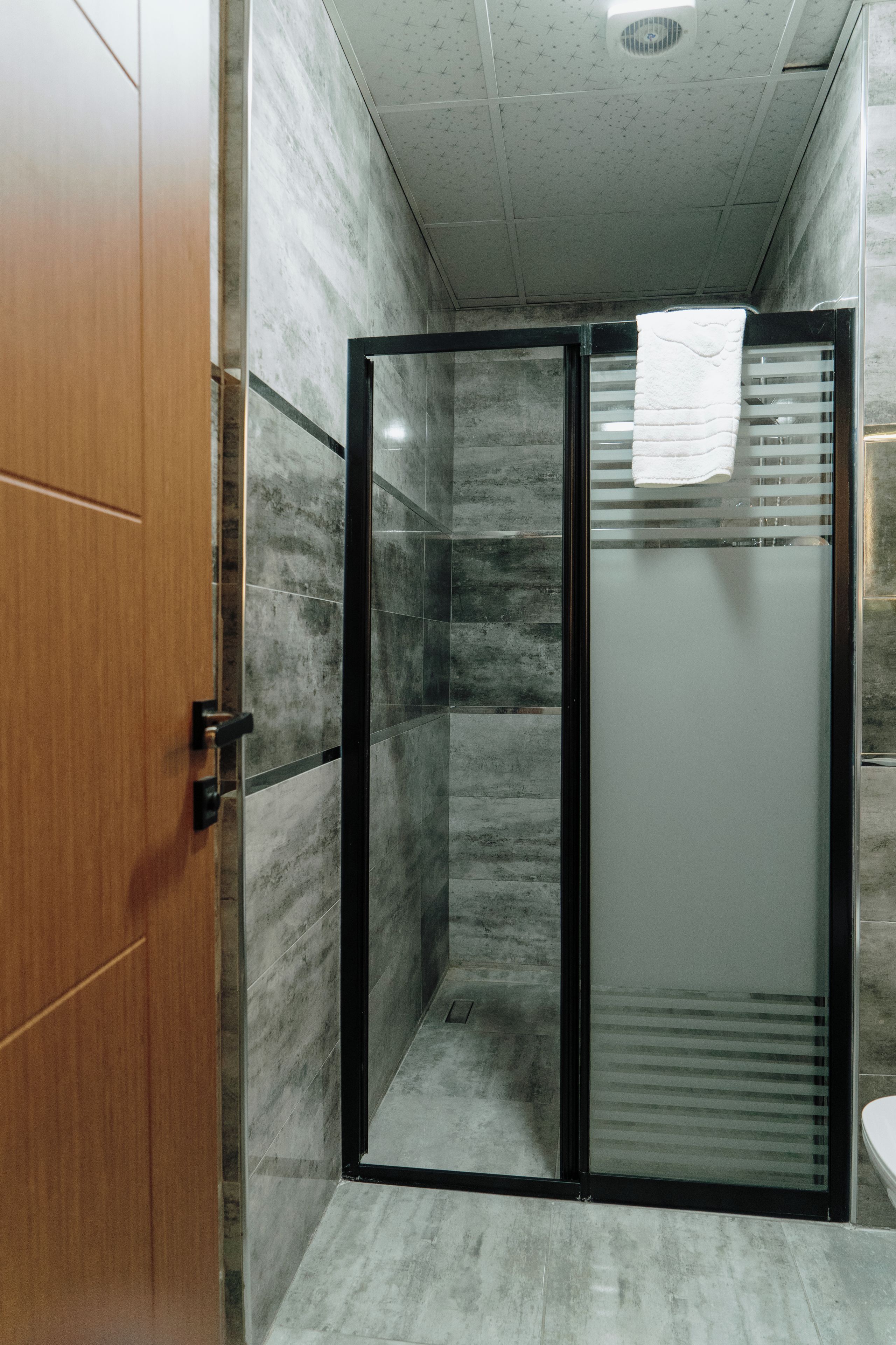 Un baño con cabina de ducha, puerta de madera y suelo de baldosas.