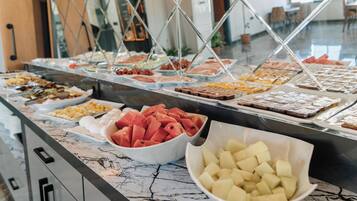 Un buffet con diverse portate, tra cui frutta e dolci.