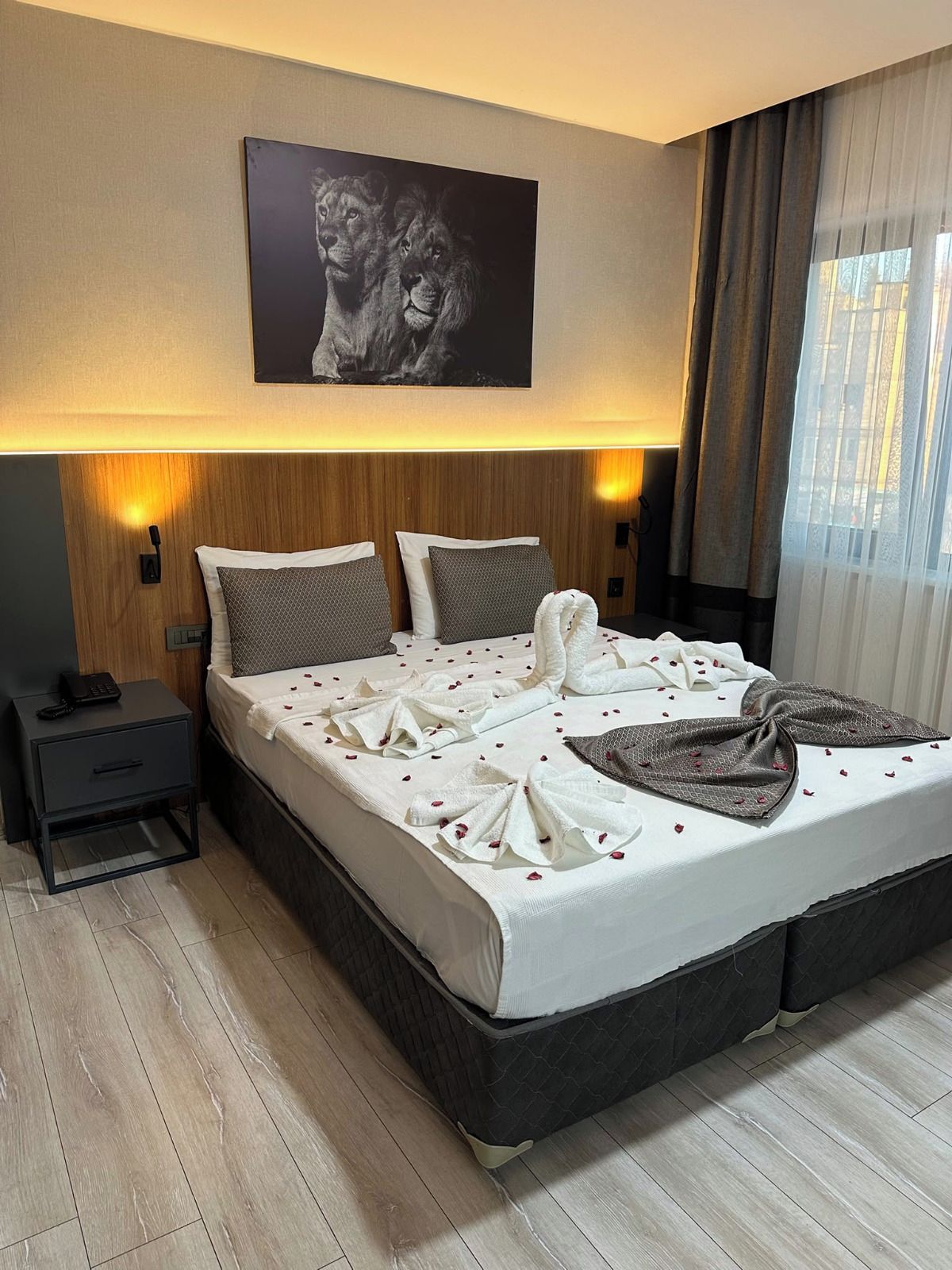 Een hotelkamer met een groot bed, nachtkastje, lamp en een schilderij aan de muur.