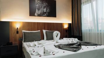Una camera d'albergo con un letto grande, due abat-jour, una testiera e un quadro incorniciato appeso al muro.