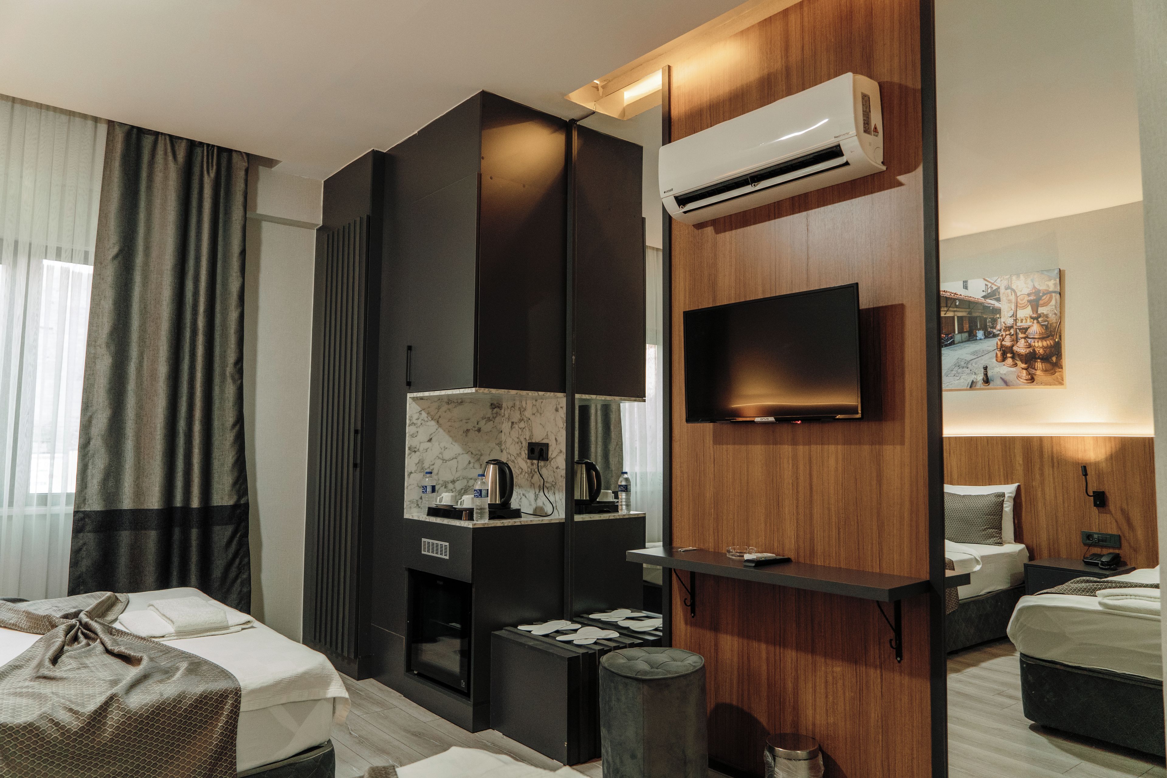Une chambre d’hôtel moderne dotée d’une télévision à écran plat, d’un minibar, d’un mur revêtu de panneaux en bois et d’un lit avec une tête de lit.