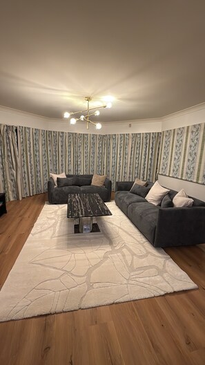 A living room with a sectional sofa, a coffee table, and patterned curtains.