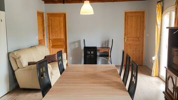 Un comedor con mesa y sillas de madera, un sofá y puertas de madera.
