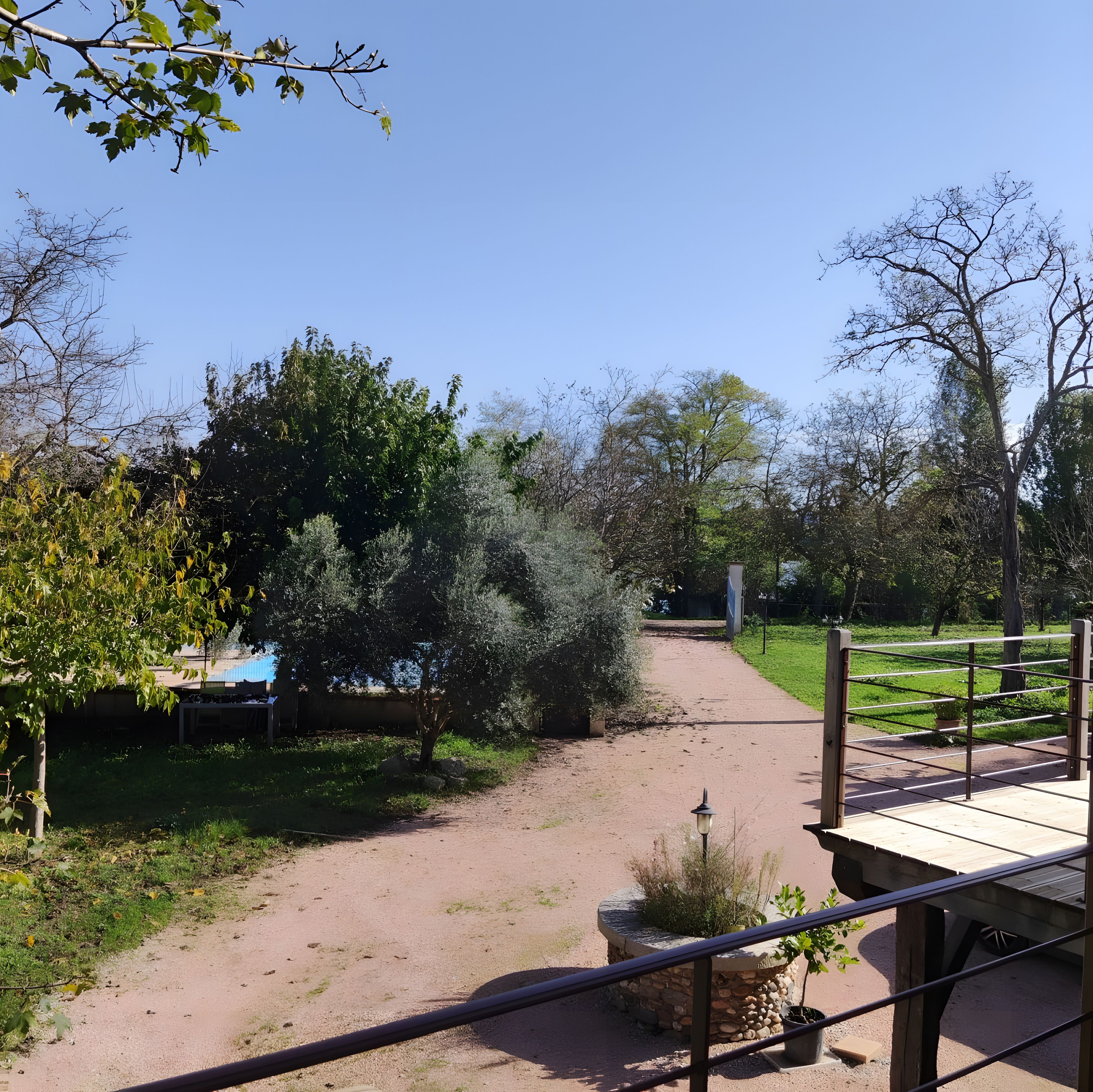 Un sentier qui traverse un parc, bordé d’arbres et doté d’une terrasse en bois.