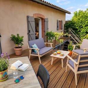 An outdoor patio with a wooden table, chairs, and a sofa.