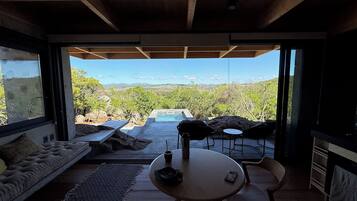 A modern interior with a view of a pool and landscape.