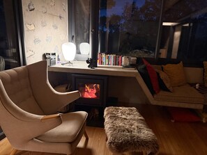 Una sala acogedora con chimenea moderna, un sillón cómodo, un sofá y una estantería.