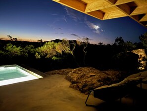 Un jacuzzi con vista a un paisaje rocoso y árboles bajo una estructura de techo de madera.
