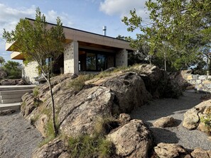 A modern building with a concrete facade, large windows, and a stone wall.