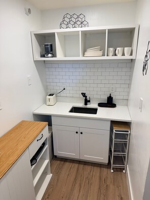 A compact kitchen with white cabinetry, a countertop, a sink, and a coffee maker. - Peaceful  studio in charming Orlando  - 5 Min Universal, Great Location. (Orlando)