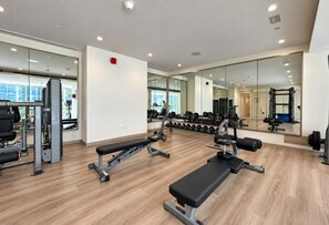 Une salle de sport équipée de matériel d’exercice, dotée de murs couverts de miroirs et d’un plancher en bois.
