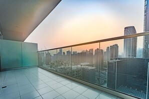 Un immeuble de grande hauteur doté d’un balcon en verre offrant une vue sur le paysage urbain au coucher du soleil.