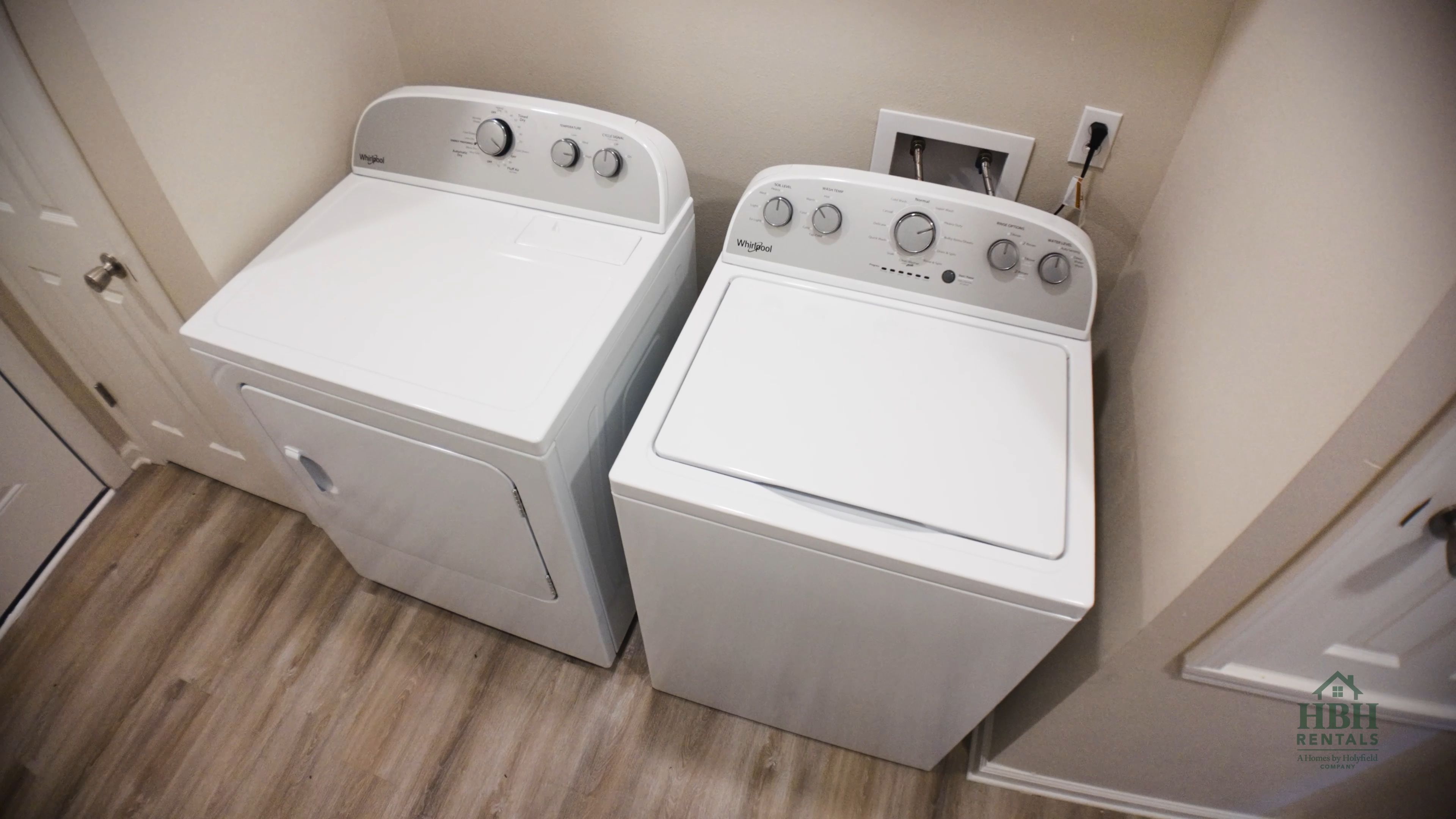Twee voorladers van Whirlpool in een wasserij met een houten vloer en een witte deur.