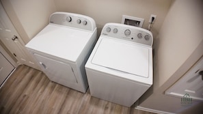 Two front-loading Whirlpool washers in a laundry room with a wooden floor and a white door.