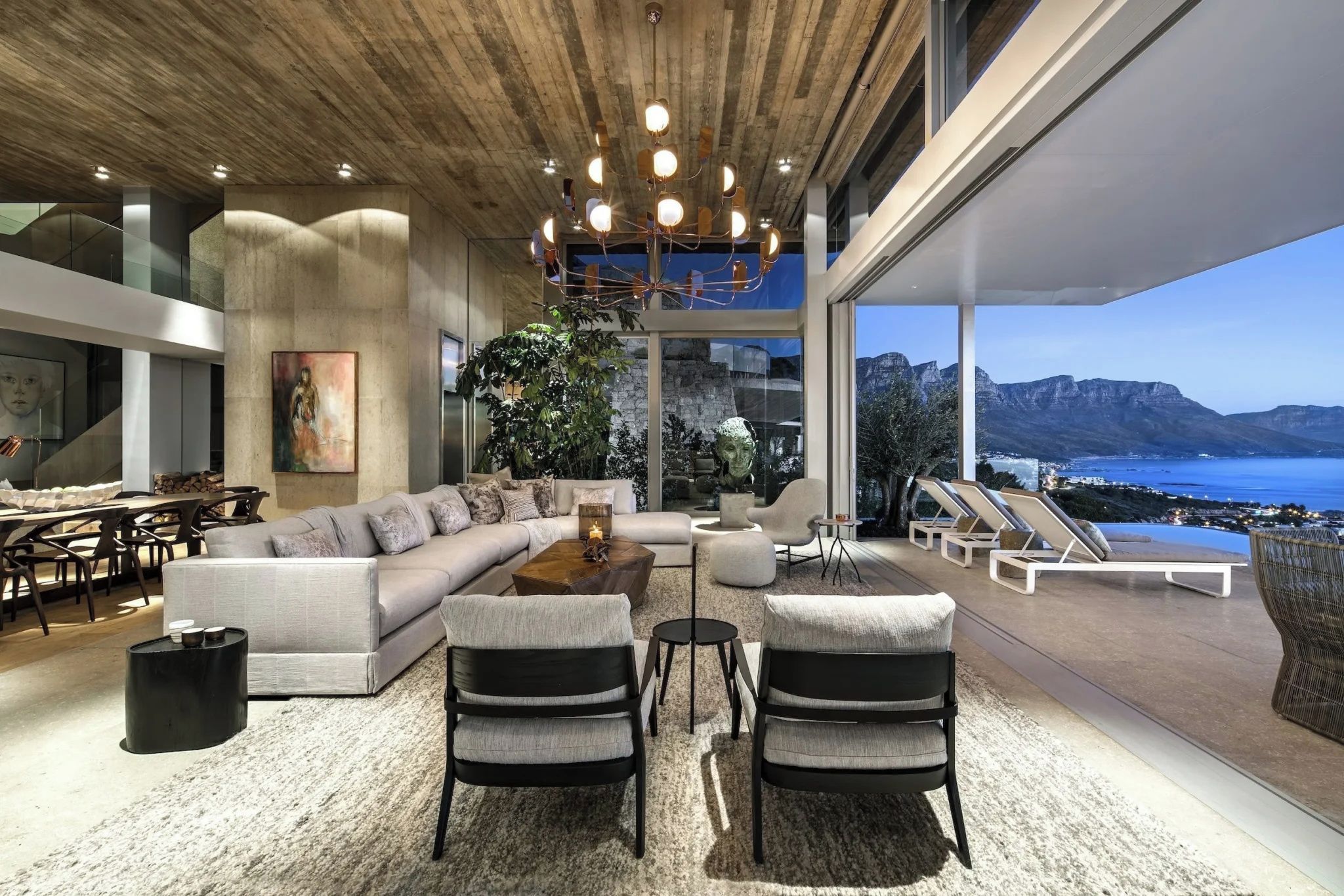 Una sala de estar moderna con un sofá grande, dos sillones, una mesa de centro y vistas al mar.