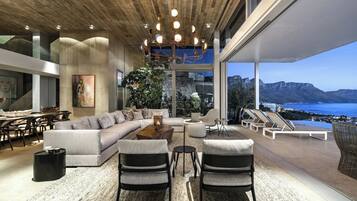 Una sala de estar moderna con un sofá grande, dos sillones, una mesa de centro y vistas al mar.