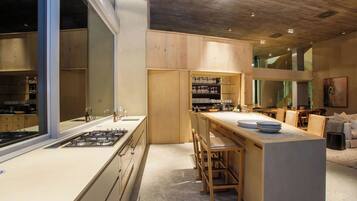 A modern kitchen with a central island, wooden cabinets, and a large window.