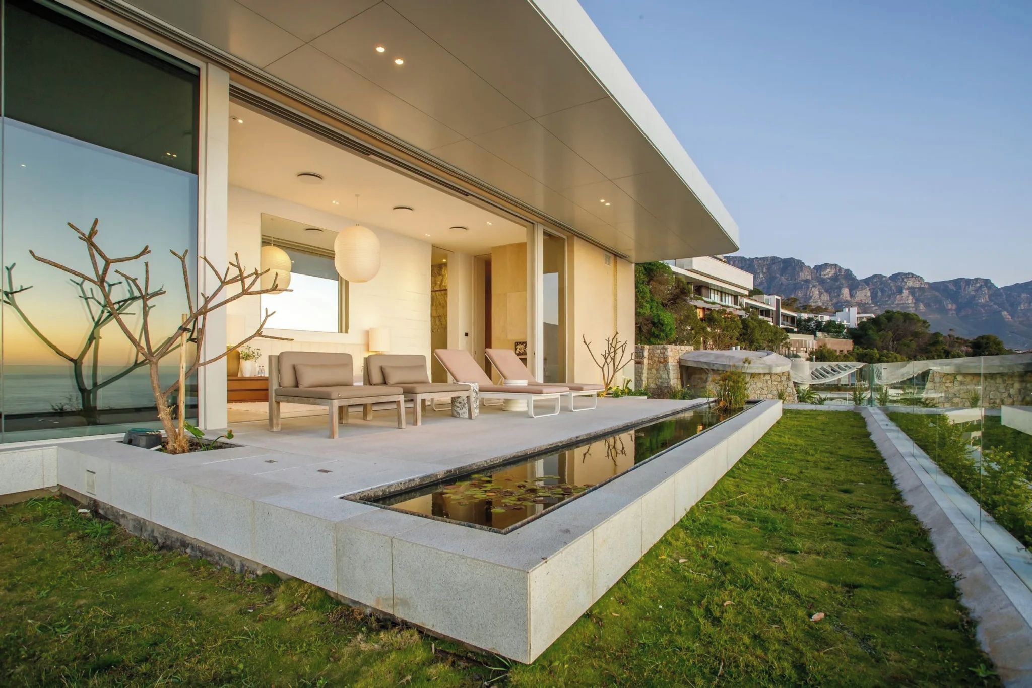 A modern house with a pool, outdoor seating, and a view of mountains.