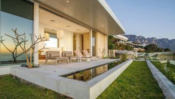 A modern house with a pool, outdoor seating, and a view of mountains.