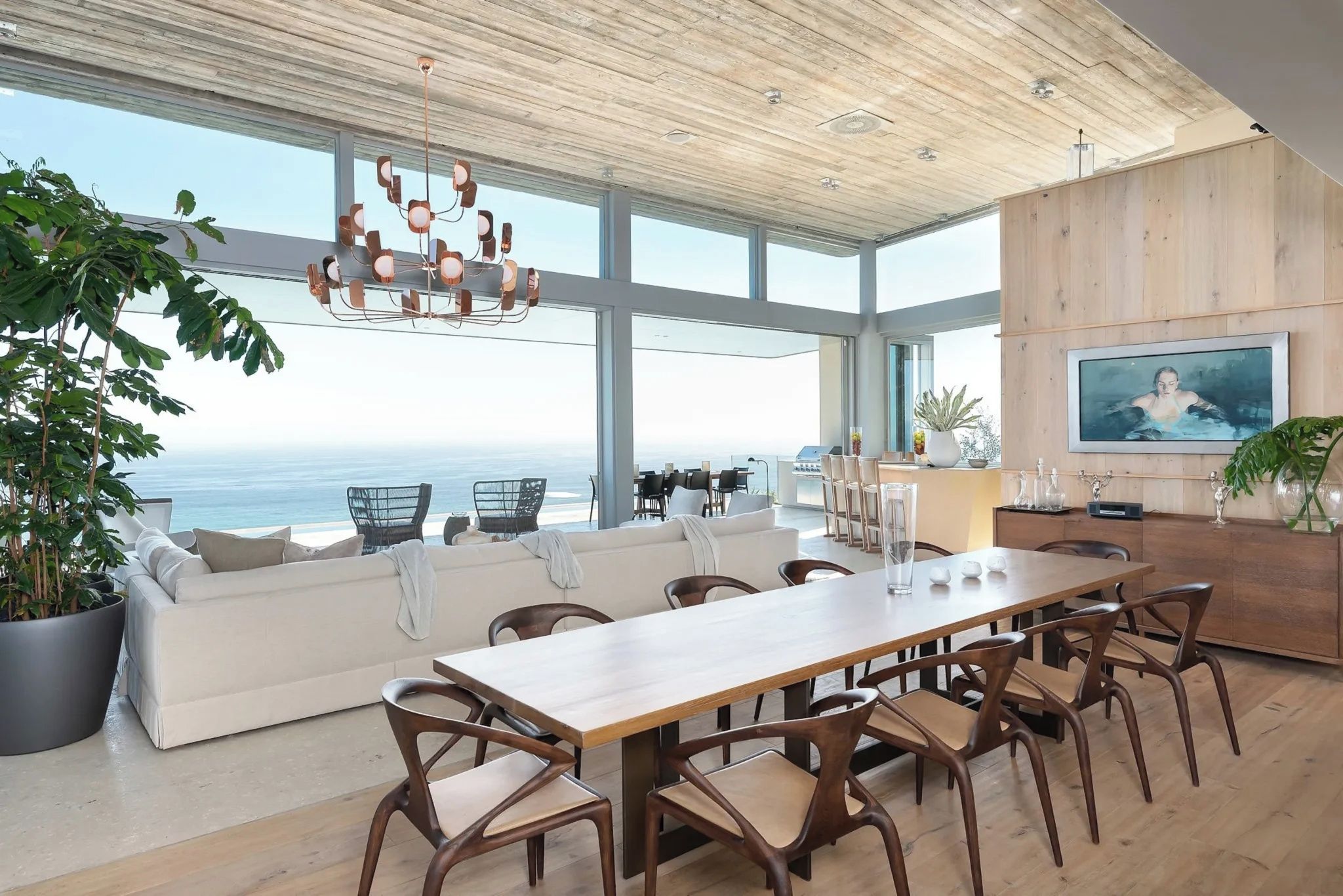 Un'ampia zona giorno con un grande tavolo da pranzo in legno, posti a sedere comodi e vista sull'oceano.