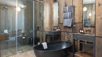 A modern bathroom with a large freestanding bathtub, a glass-enclosed shower, and wooden paneling.