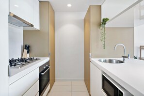 A modern kitchen with white cabinetry, a stainless steel sink, and a gas stove. - Skyline Serenity 2BR in Melbourne CBD, Sky Gym & Pool (Melbourne)